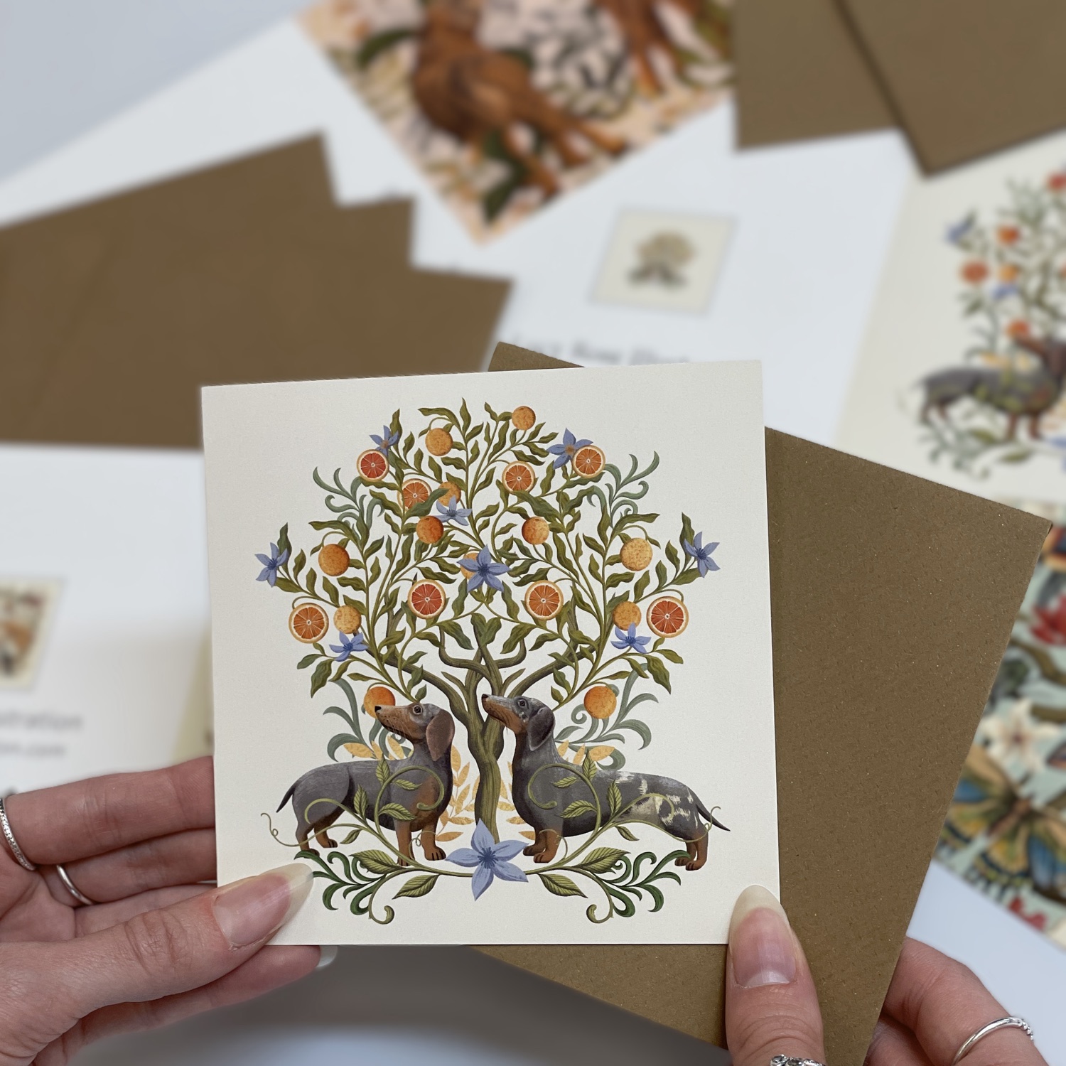 A greeting card with two dachshunds beneath an orange tree