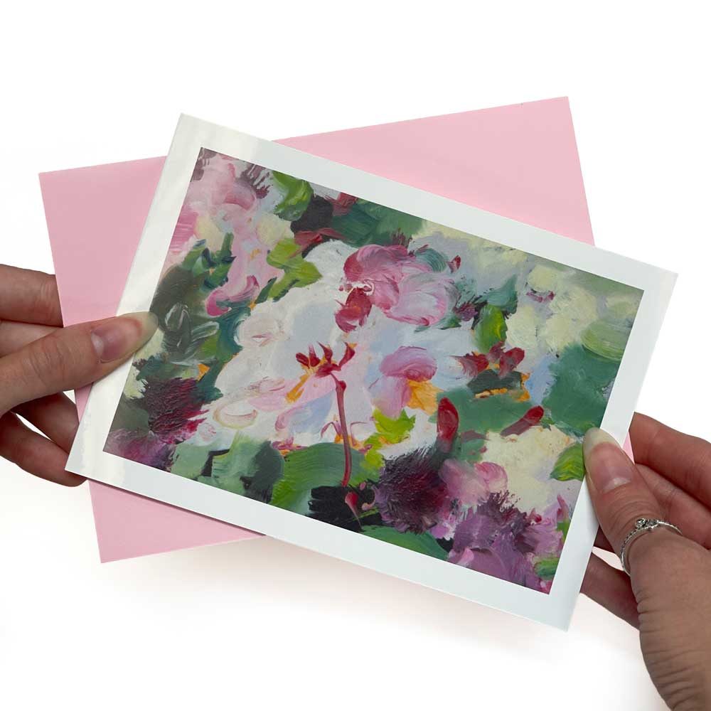 A pink and green abstract floral greeting card with a pink envelope