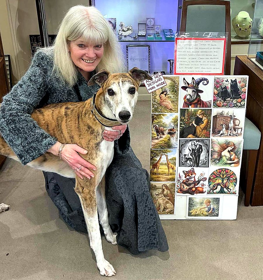 Jean Armstrong with her greyhound beside a display board of her greeting card designs
